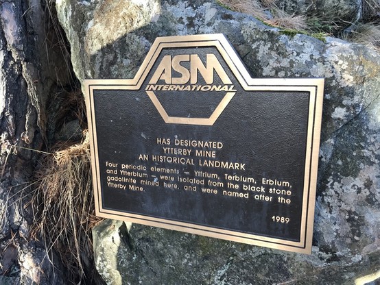 A sign from ASM International noting that the mine at Ytterby has been designated as a historical landmark.