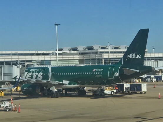 Photo of a jetblue plane painted dark green and with “NY jets” text  (depicts the  other side from the other photo) 