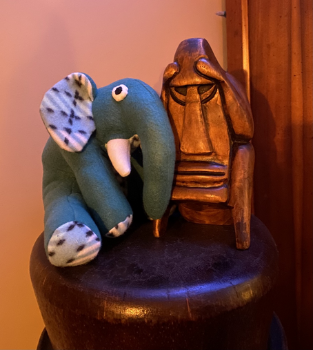 Stuffed elephant toy and a wooden carving of a suffering bastard 