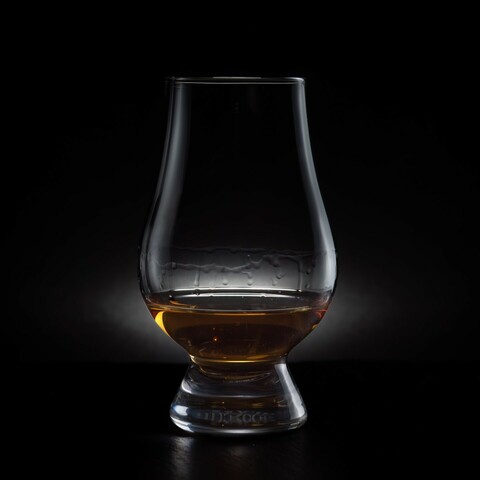 A Glencairn glass of whisky against a dark backdrop