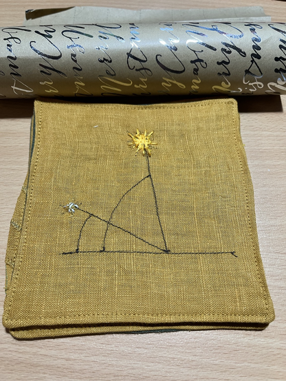 Summer v winter Sun angle depicted as embroidery on mustard linen