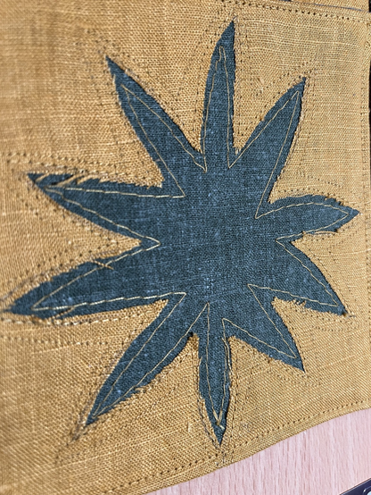 Green foliage in relief behind mustard linen