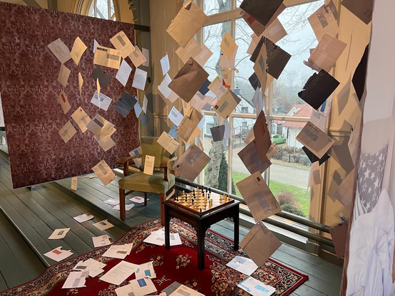 ‘Zwevende’ enveloppen in een ingerichte huiskamersetting, als deel van de expositie NIEMANDS NUMMER EEN.