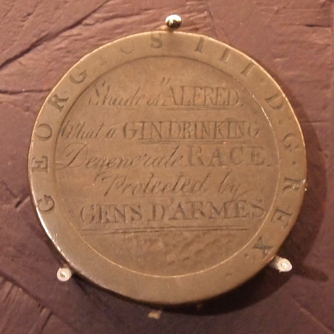 Close-up of a defaced coin.
Hand-etched on the centre: "Shade of ALFRED. What a GIN DRINKING Degenerate RACE. Protected by GENS D'ARMES"
Around the edge, "GEORGIUS III · D.G · REX."
