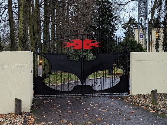 Ein Flügeltor vor einer Einfahrt auf dem das Triple X und das Batman Logo angebracht sind.