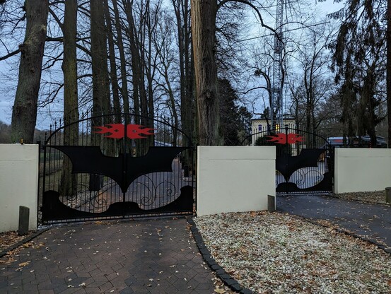 Zwei Flügeltore zu zwei Einfahrten auf denen das Triple X und das Batman Logo angebracht sind.