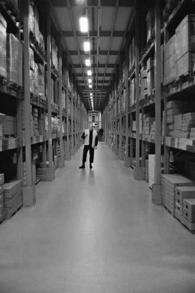 Black and white photo of my wife looking for the right shelves at an IKEA warehouse.
