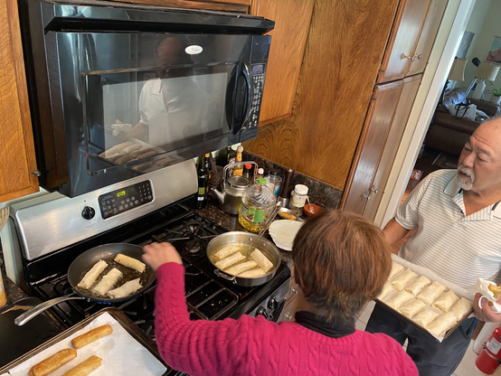 Parents frying egg rolls 