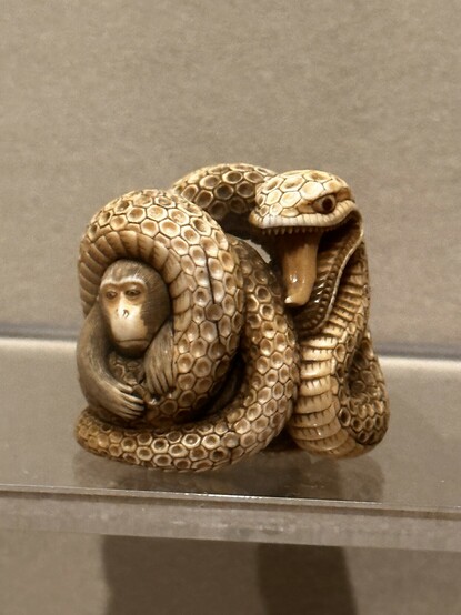 An ivory Netsuke representing a snake wrapped around a monkey. 