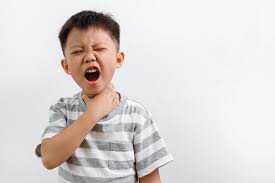Young boy holding throat in pain