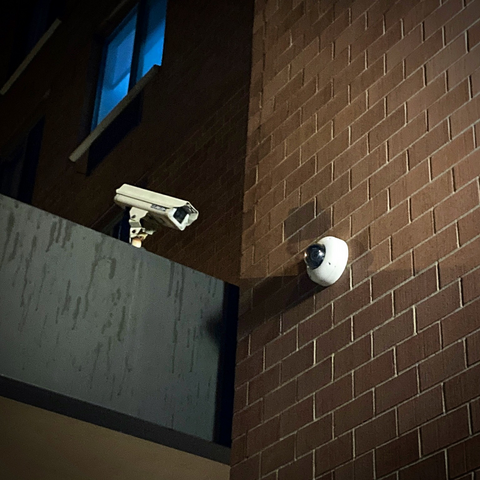 a photo of a surveillance camera pointing directly and only at a surveillance camera on an adjacent wall.