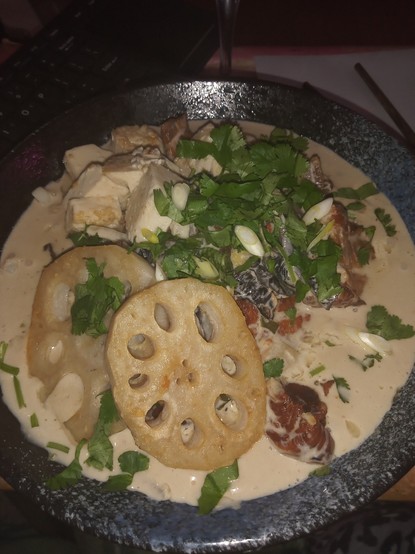 Blue bowl with creamy sauce, lotus root, coriander and belly pork
