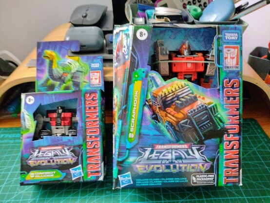 Photo of two Transfomer toys in their boxes on a desk.