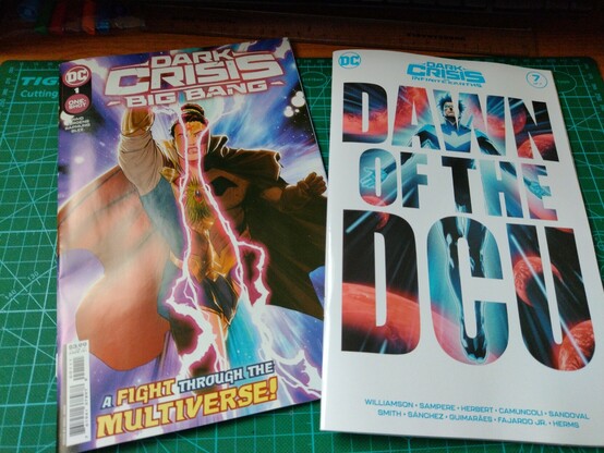 Photo. Two comic books on a desk. Dark Crisis Big Bang 1 and Dark Crisis 7.