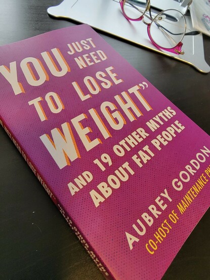 "You just need to lose weight and 19 other myths about fat people" by Aubrey Gordon. Pink cover on a desktop with glasses visible in the background.
