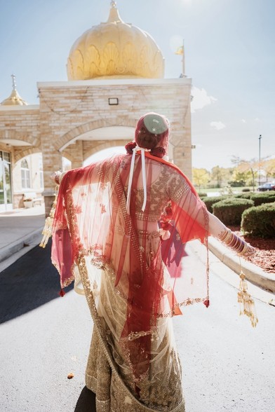 Sikh Bride spinning in her sari with the Sikh temple of Wisconsin in the background 