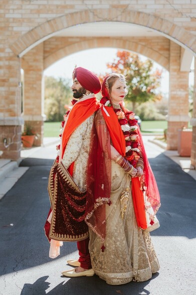 Sikh Bride and Groom standing back to back with the Sikh temple of Wisconsin in the background 