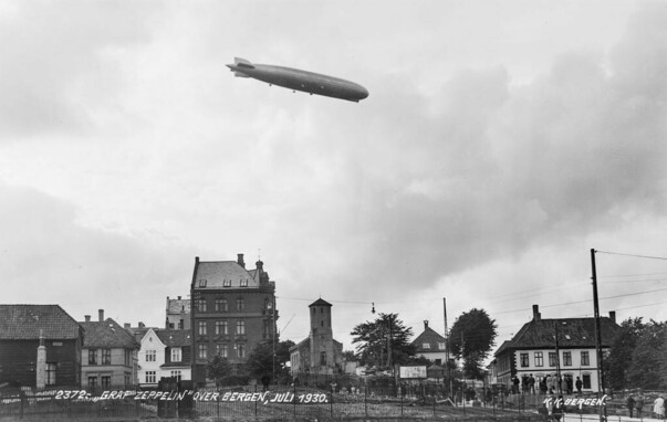 A historical photo in black and white from 1030, showing an airship above some buildings.