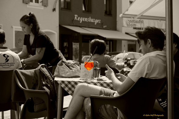 schwarz weis Foto von einem Straßencafé. Das Getränk ist aber farbig dargestellt. 