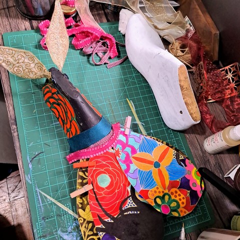 Shoe last now has colorful wings, looks more like a giant insect. Gold antennae. Colorful body. No legs yet.