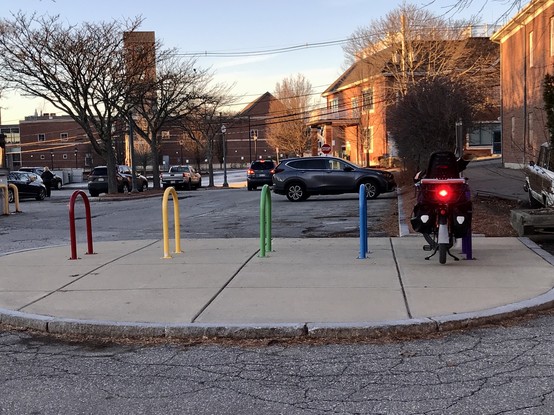 Cargo bike parked at a set of rainbow bike racks. 