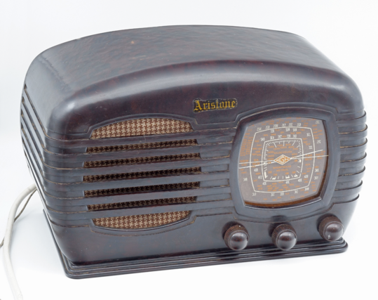 Another vintage radio, this one has an arched top, a deep brown bakelite colour and matching shapes for the grille and the dial, which are both rounded square shapes.