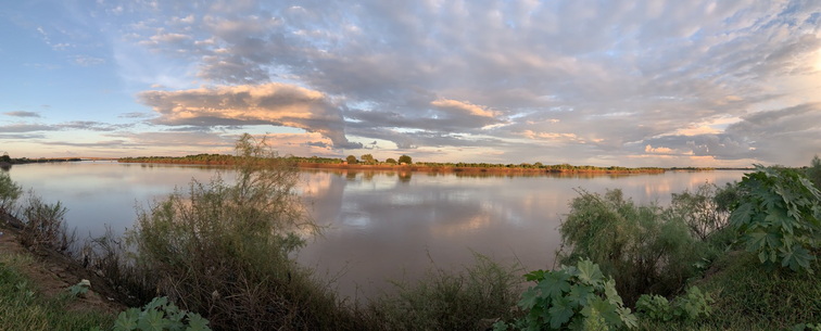 The Blue Nile at sunset. The sky is a pinkish red, peeking through light grey cloud. 