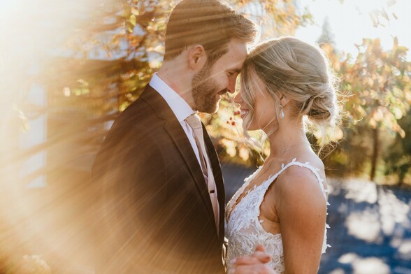 Bride and groom at golden hour facing each other with a golden sun flare