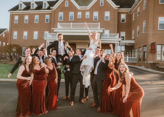 Bride and groom at golden hour picked up and carried by their wedding party