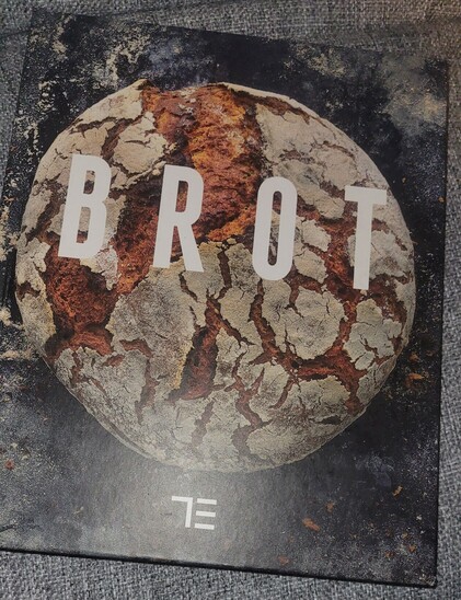 Foto des erwähnten Buches "Brot". Auf dem Einband ist ein rustikaler, runder Laib mit bemehlter, aufgerissener Kruste zu sehen. 
