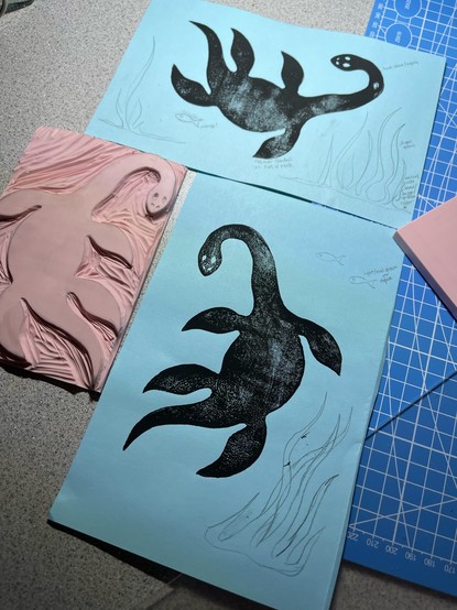 Linocut test prints of a plesiosaur frolicking 
