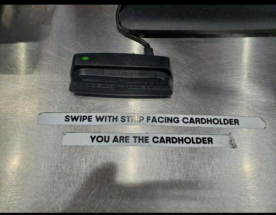 A card reader with two printed labels glued on: swipe with strip facing cardholder + you are the cardholder 
