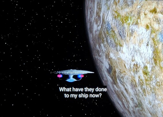 The Enterprise D is shown in orbit of a planet. Closed caption reads, "What have they done to my ship now?"