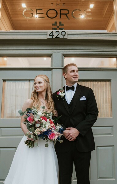 Bride and groom standing dramatically in front of The George and Madcap Lounge (a Milwaukee event venue) on their wedding day. 