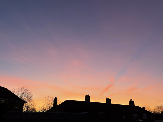 Silhouetted houses with a glowing sky of purple, pink, and gold
