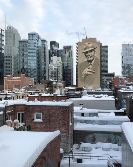 Image of the Montreal skyline with a building with a full length Leonard Cohen mural on it in the foreground