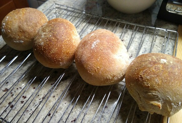Four round small rolls are shown cooling on a rack