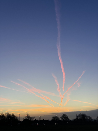 Streaks of pink cloud across a blue sky as the sun rises golden below