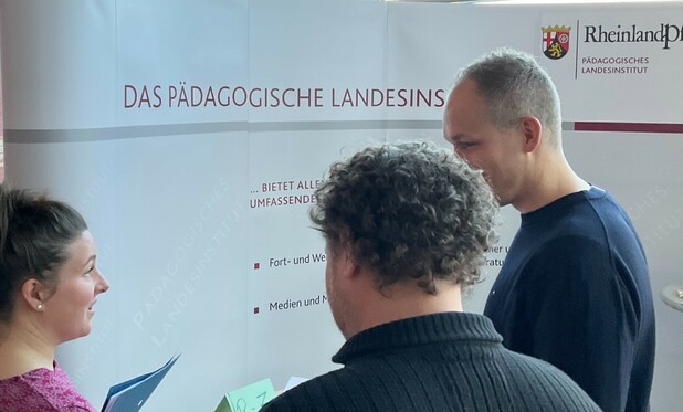 Drei Menschen im Gespräch, Austausch am Stand des Pädagogischen Landesinstituts auf dem Fachtag