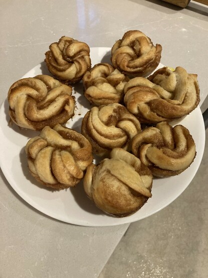 White plate of cinnamon rolls on a countertop.