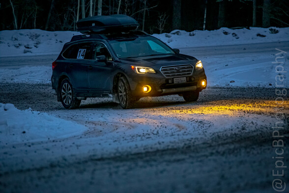 Same car, in the dark. Yellow fog lights are illuminating the gritty snow