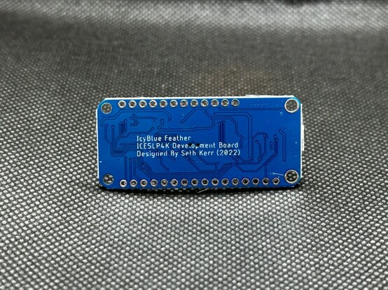 IcyBlue Feather back side. Blue PCB sitting on an illuminated back background.