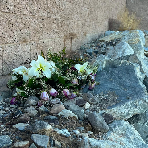 A bouquet of flowers tossed on the ground at the side of a paved trail. 