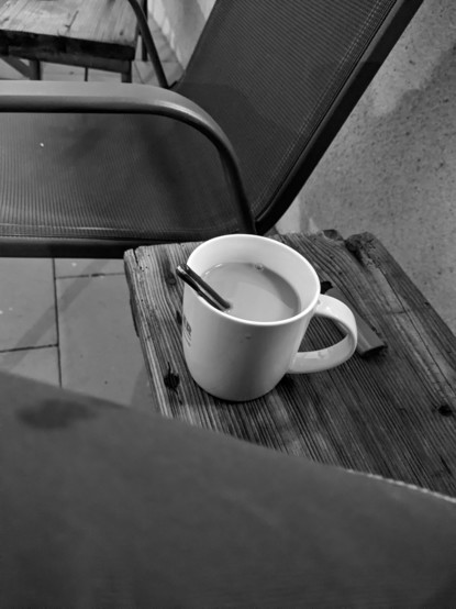 Schräg von oben herab fotografierter Kaffebecher mit Löffel. 