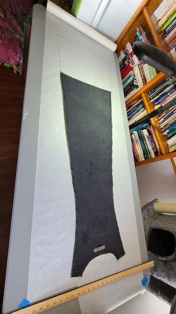 Black dress piece from the deconstructed dress laid out on white pattern paper and traced. 