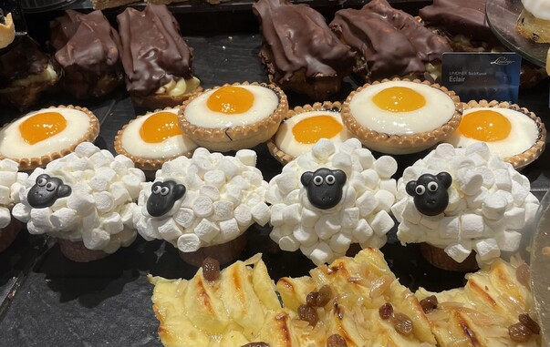 Auslage mit Törtchen: Eine Reihe mit solchen, die wie Spiegeleier aussehen, darunter wie Shaun das Schaf.