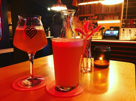 A branded stem glas, a pint and a wall of vinyl records at The Big Romance