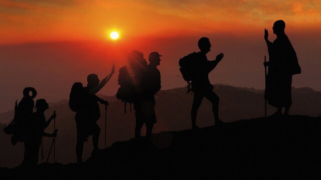 Silouette of hikers meeting a Buddhist monastic on the road.