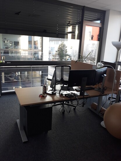 Photo of my desk at work. Just a table, 2 monitors and a laptop on a stand.