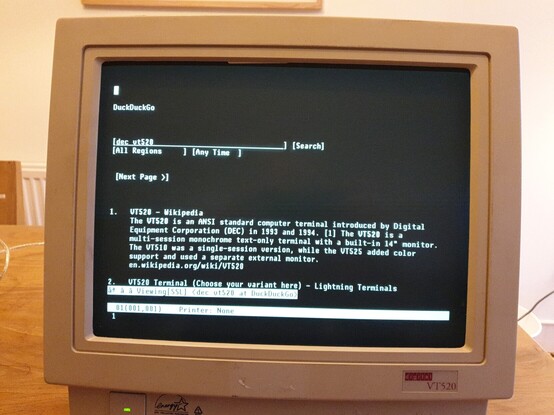 A photo of a DEC VT520 hardware text terminal, displaying Duckduckgo search results for the string "Dec vt520", with the Wikipedia page summary as the top result. 